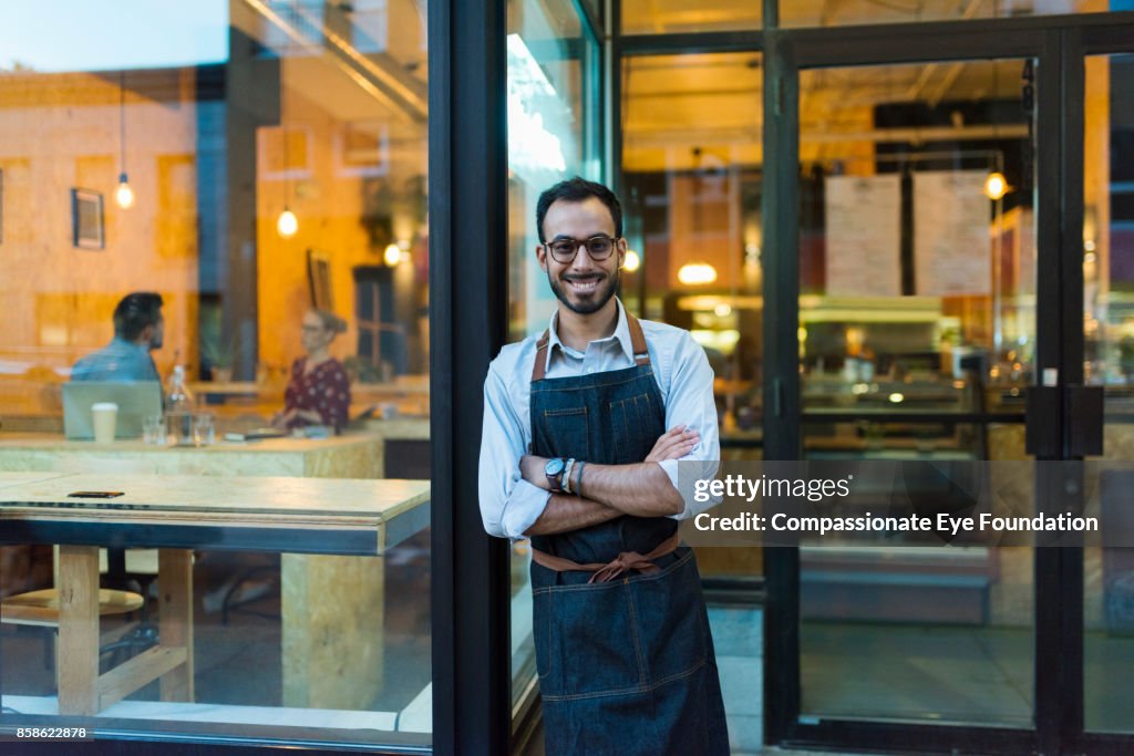 Portrait of business owner standing outside cafe