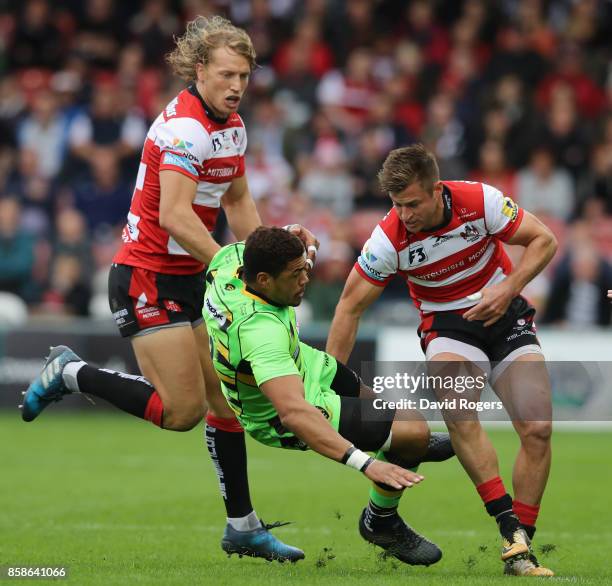 Luther Burrell of Northampton is tackled by Henry Trinder and Billy Twelvetrees during the Aviva Premiership match between Gloucester Rugby and...