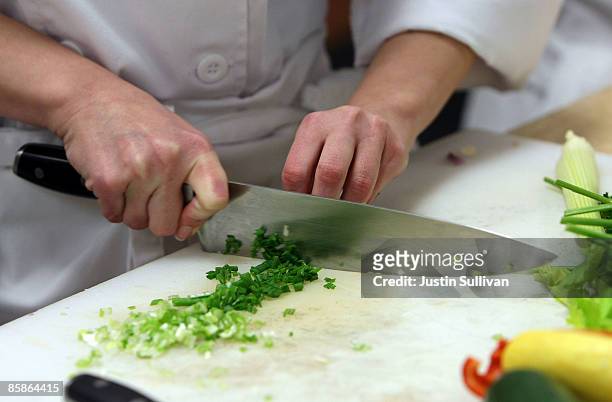Culinary student uses a chefs knife to cut green onions during a butchery class at the Le Cordon Bleu program at California Culinary Academy April 8,...
