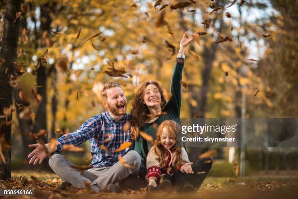happy ginger family having fun among autumn leaves at the park. - throwing leaves stock pictures, royalty-free photos & images