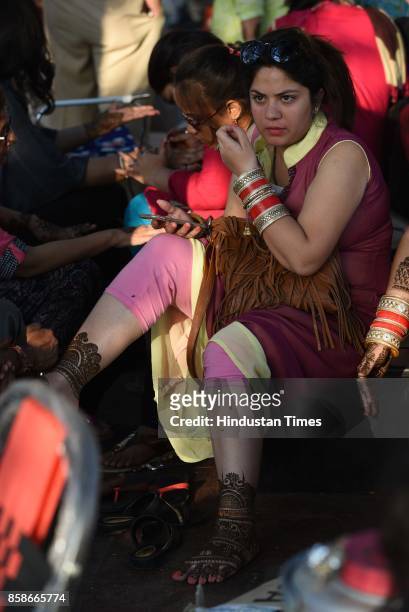 Women have their hands decorated with henna Mehndi on the eve of Karva Chauth at Hanuman Temple, Connaught Place, on October 7, 2017 in New Delhi,...