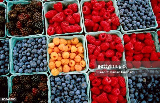 raspberry, blueberry and blackberry punnets at farmers market. - berry stockfoto's en -beelden