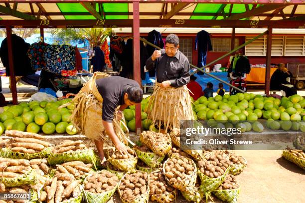 men in grass skirts with sweet potatoes at central market. - insel tongatapu stock-fotos und bilder