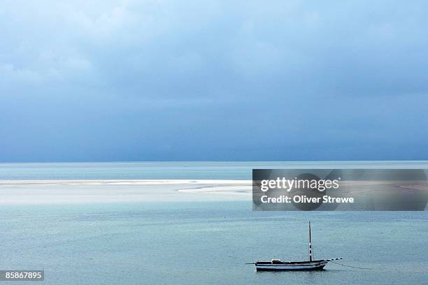 a fishing dhow anchored of the coast of vilanculos, mozambique - mozambique beach stock pictures, royalty-free photos & images