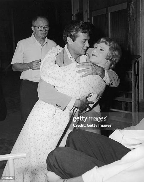 Austrian-born film director Billy Wilder watches from the background as actor Tony Curtis dips actor Jack Lemmon, who is dressed in costume as a...