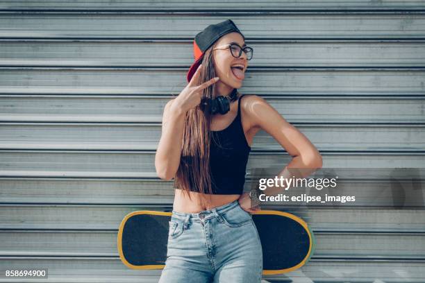 close up of a teenage girl holding skateboard - girl headphones imagens e fotografias de stock