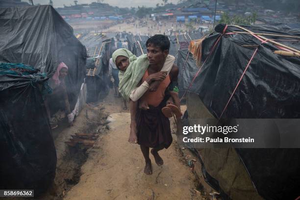 Rohingya man carries his handicapped mother to her tent October 7, Thainkhali camp, Cox's Bazar, Bangladesh. Well over half a million Rohingya...