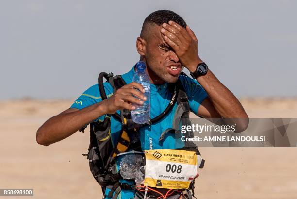 Morocco Mohamed el-Morabity, pours water on his face as he runs to win the first edition of the Ultra Mirage El Djerid marathon in the desert near...