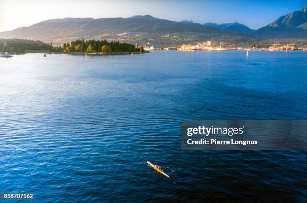 nonrecognizable rowers in burrard inlet, stanley park in background, vancouver, british columbia, canada - inlet stockfoto's en -beelden