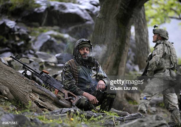 An Afghan National Army soldier smokes during a mission for searching weapon cache in Nishagam, in Afghanistan's eastern Kunar province on April 8,...