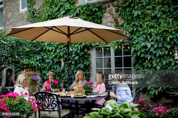 dineren onder de tuin parasol met vrienden - parasol stockfoto's en -beelden