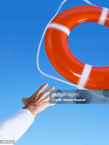 hand reaching for life ring against blue sky - ring toss bildbanksfoton och bilder