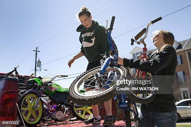 Maddie Myer and Heather Cromartie unload donated bicycles froma pickup truck as they volunteer during a bicycle collection drive on April 4, 2009 for...