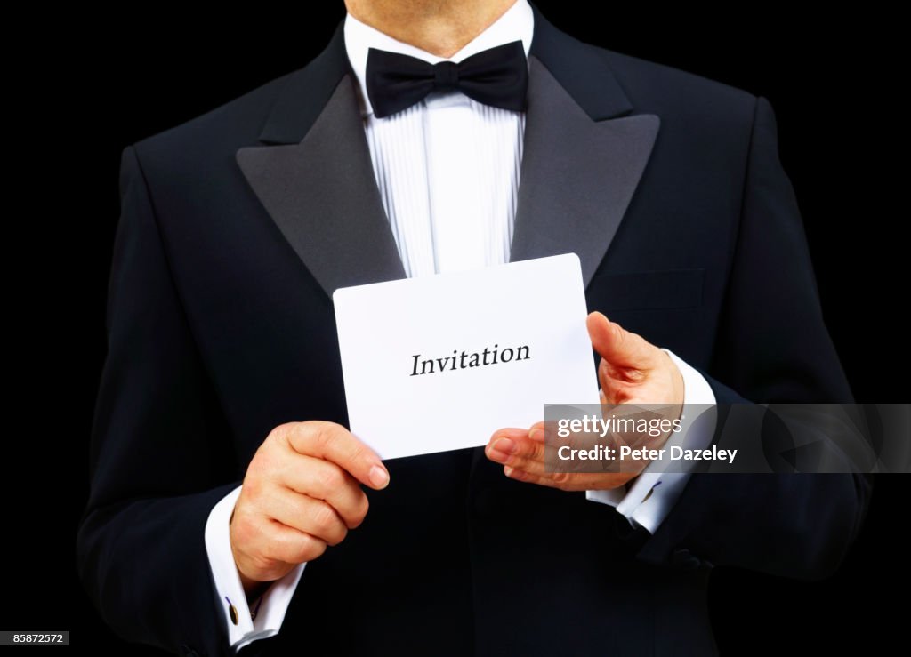 Butler holding invitation in two hands.