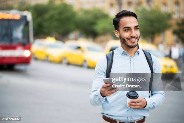 latino man met mobiele app om te roepen crowd-sourced taxi - colombian ethnicity stockfoto's en -beelden