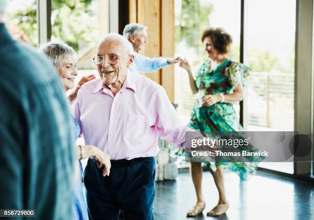 smiling senior couple dancing together during dance in community center - baile de salón fotografías e imágenes de stock