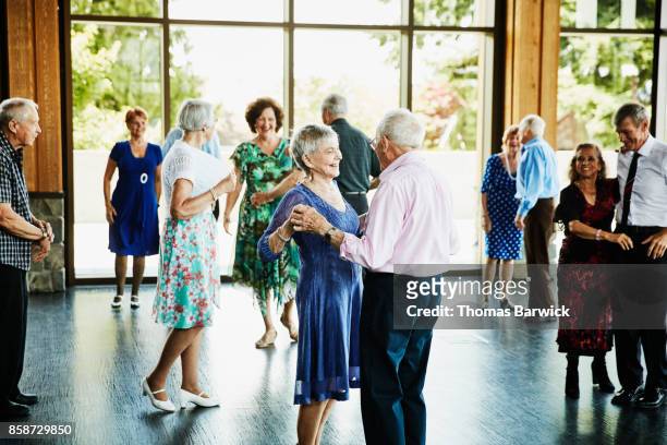 Smiling couple holding hands and finishing dance in community center