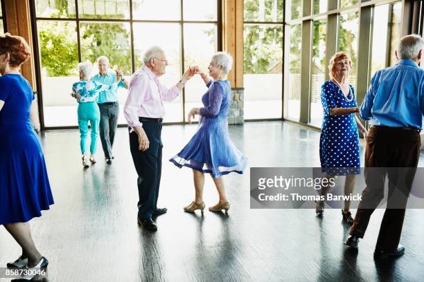 senior couple dancing together with friends in community center - ballroom stockfoto's en -beelden