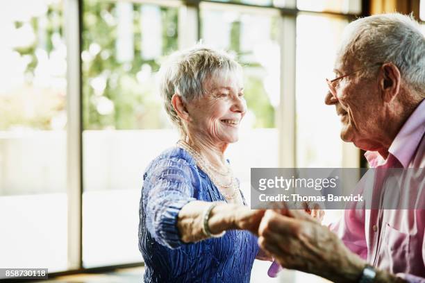 Smiling senior couple dancing together in community center