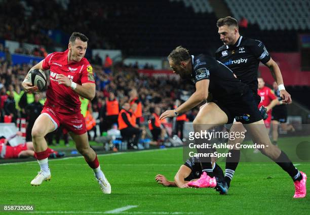 Scarlets' Gareth Davies evades the tackle of Ospreys' Rhys Webb during the Guinness Pro14 Round 6 match between Ospreys and Scarlets at Liberty...