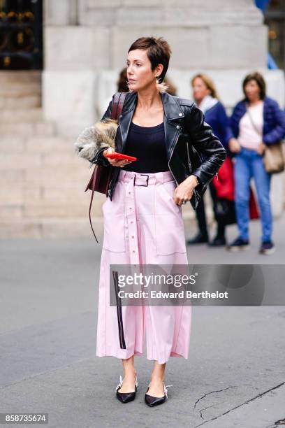 Guest wears a black leather jacket, a black top, pink pants, outside Stella Mccartney, during Paris Fashion Week Womenswear Spring/Summer 2018, on...