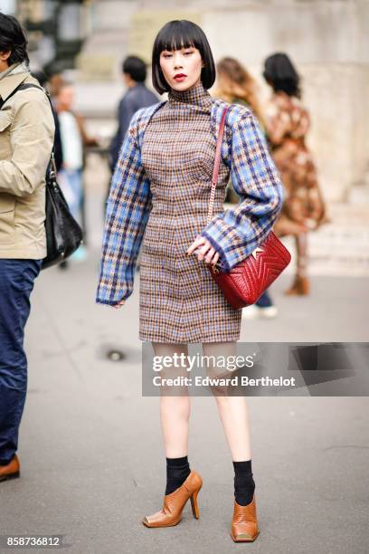 Mademoiselle Julia wears tartan sleeves, a dress, a red bag, brown shoes, black socks, outside Stella Mccartney, during Paris Fashion Week Womenswear...