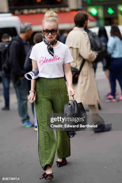 Guest wears sunglasses, a white t-shirt "blondie" print, green pants outside Stella Mccartney, during Paris Fashion Week Womenswear Spring/Summer...