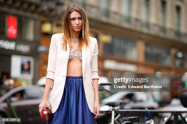 Landiana wears a blazer jacket, a blue pleated skirt, a red clutch, outside Stella Mccartney, during Paris Fashion Week Womenswear Spring/Summer...