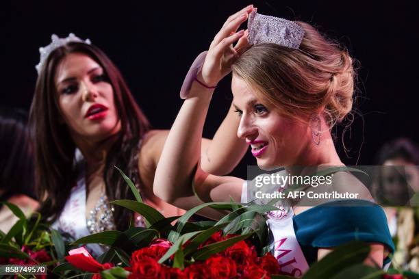 Miss Belarus Aleksandra Chichikova , winner of the Miss Wheelchair World contest beauty pageant, adjusts her crown with the helping hand of second...