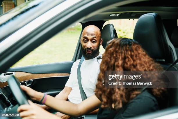 father in discussion with daughter while teaching her to drive - front passenger seat stock-fotos und bilder