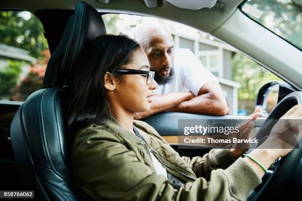 father leaning through window of car while teaching daughter to drive - learning to drive stock pictures, royalty-free photos & images