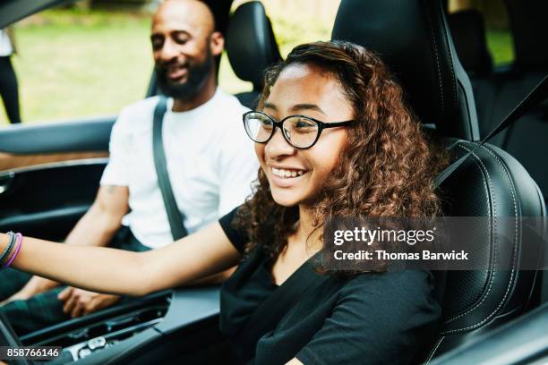 smiling young woman in drivers seat of car while taking driving lesson from father - learning to drive ストックフォトと画像