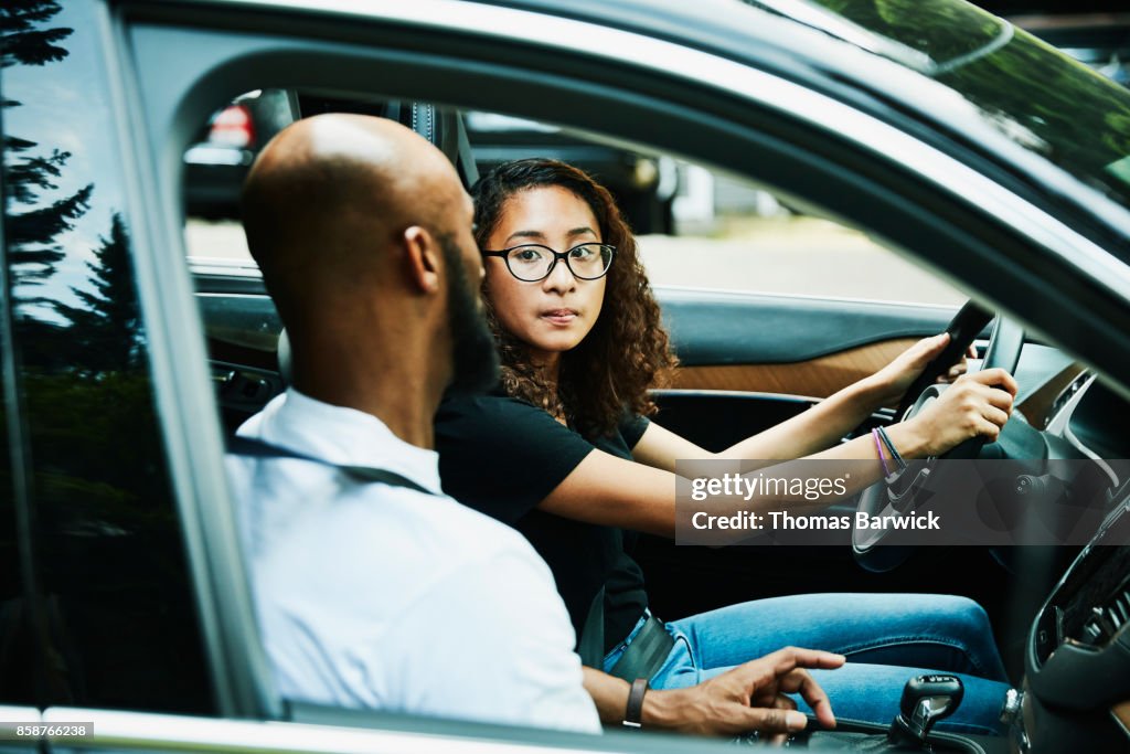 Daughter listening to fathers instructions while sitting in car before driving lesson