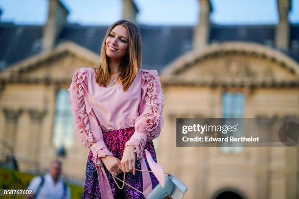 Landiana wears a pink top, purple striped shiny pants, a bag, outside Louis Vuitton, during Paris Fashion Week Womenswear Spring/Summer 2018, on...