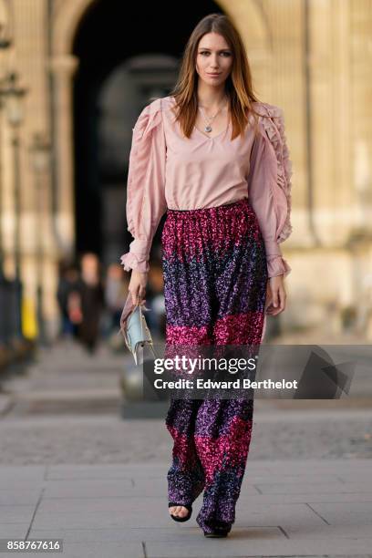 Landiana wears a pink top, purple striped shiny pants, a bag, outside Louis Vuitton, during Paris Fashion Week Womenswear Spring/Summer 2018, on...