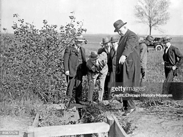 Group of unidentified men standing outdoors at the Leopold and Loeb crime scene durnig the investigation of the Bobby Franks murder case. One of the...