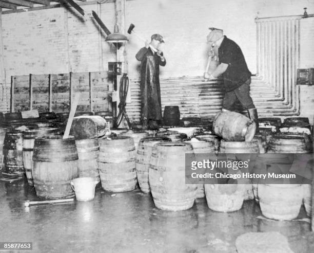 Two men destroy barrels of confiscated alcohol by taking axes to the contraband, North Dakota, 1929.