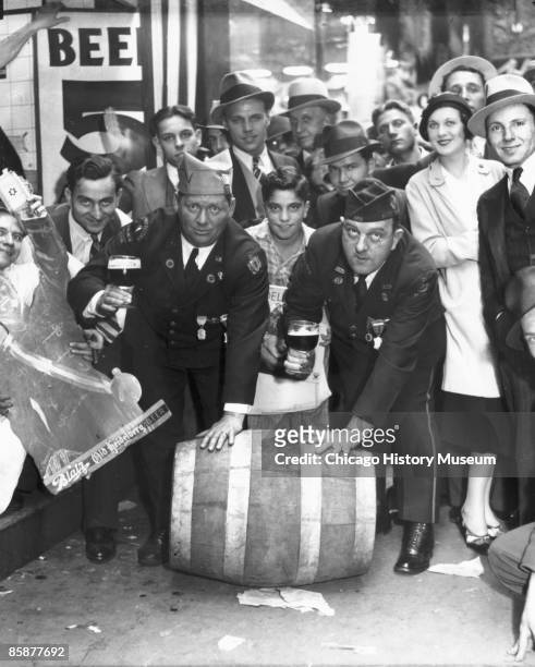 View of men and women celebrating the repeal of Prohibition by rolling down a barrel of alcohol and toasting the 18th Amendment's demise, Chicago,...