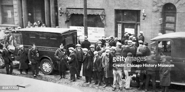 Police and spectators gather in front of the infamous garage where the St. Valentine's Day Massacre occurred, Chicago 1929. The event became a symbol...