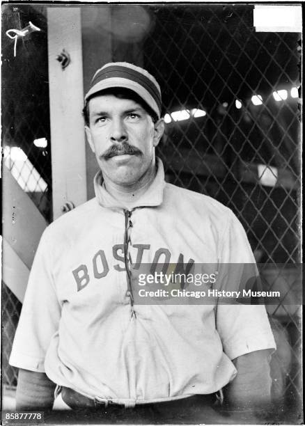 Candy LaChance, first baseman for the Boston American League baseball team, standing in front of concourse netting at South Side Park which was...