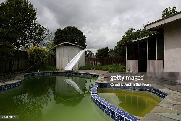 Neglected pool is green with algae at a foreclosed home April 9, 2009 in Concord, California. Unseasonably warm weather for Northern California in...