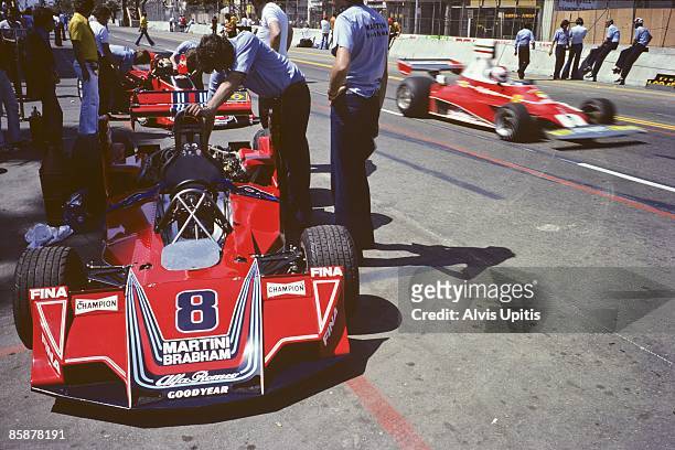 Brabham Alfa Romeo sits in pit lane as the Ferrari 312T of Clay Regazzoni passes by at the first United States Grand Prix West held on March 28, 1976...