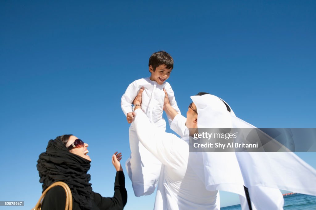 Arab woman watching man lifting boy.