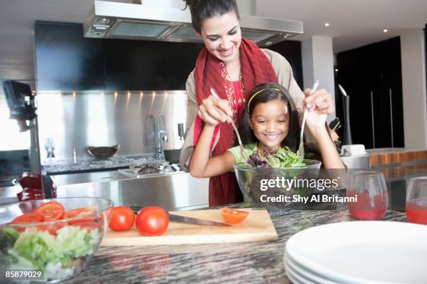 mother with daughter mixing salad in bowl. - jalabib stock pictures, royalty-free photos & images