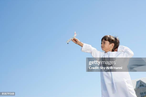arab boy holding toy airplane against sky. - arabic boy stock pictures, royalty-free photos & images