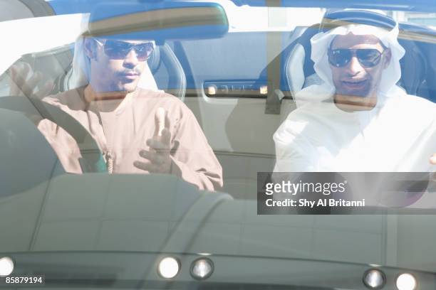 two arab men wearing sunglasses sitting in a car. - arab driving stock-fotos und bilder