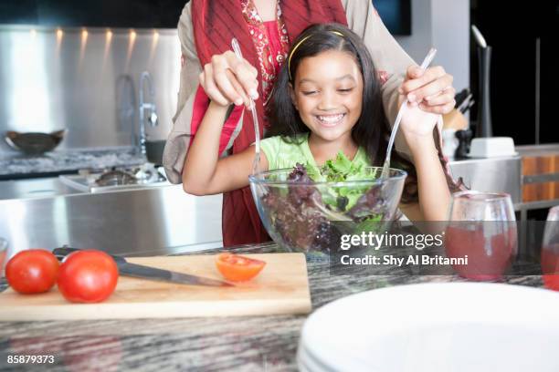 mother with daughter mixing salad in bowl. - jalabib stock pictures, royalty-free photos & images