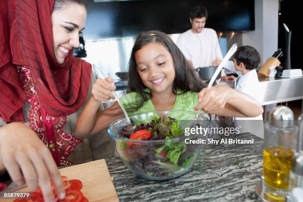mother with daughter mixing salad in bowl. - jalabib stock pictures, royalty-free photos & images