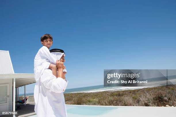 arab boy sitting on father's shoulders. - arab villa stockfoto's en -beelden