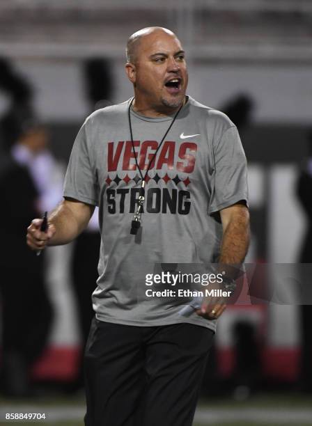 Head coach Tony Sanchez of the UNLV Rebels wears a "Vegas Strong" shirt as he watches his players warm up before their game against the San Diego...